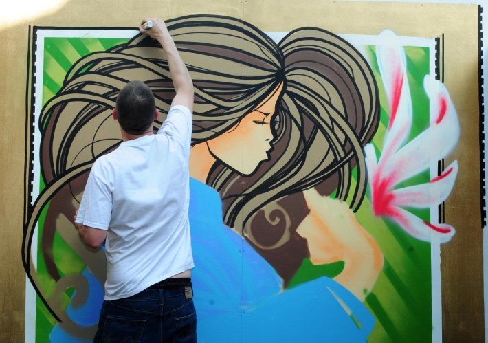 Graffiti artist Inkie paints a mural in garden of the cafe DoLii Coffee